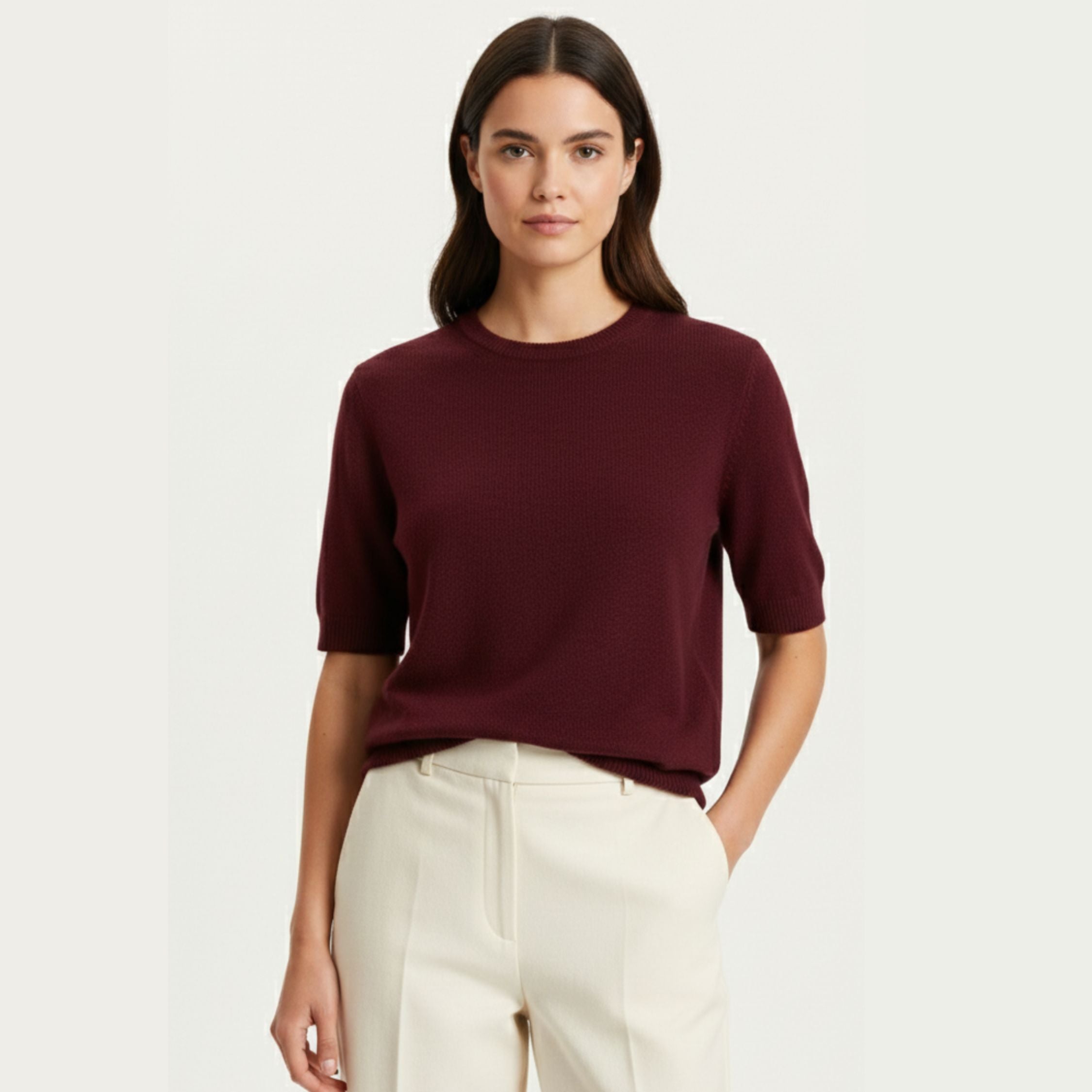 Female model wearing a Maroon Red regular-fit knitted T-shirt made of 100% cashmere pashmina, paired with white trousers.