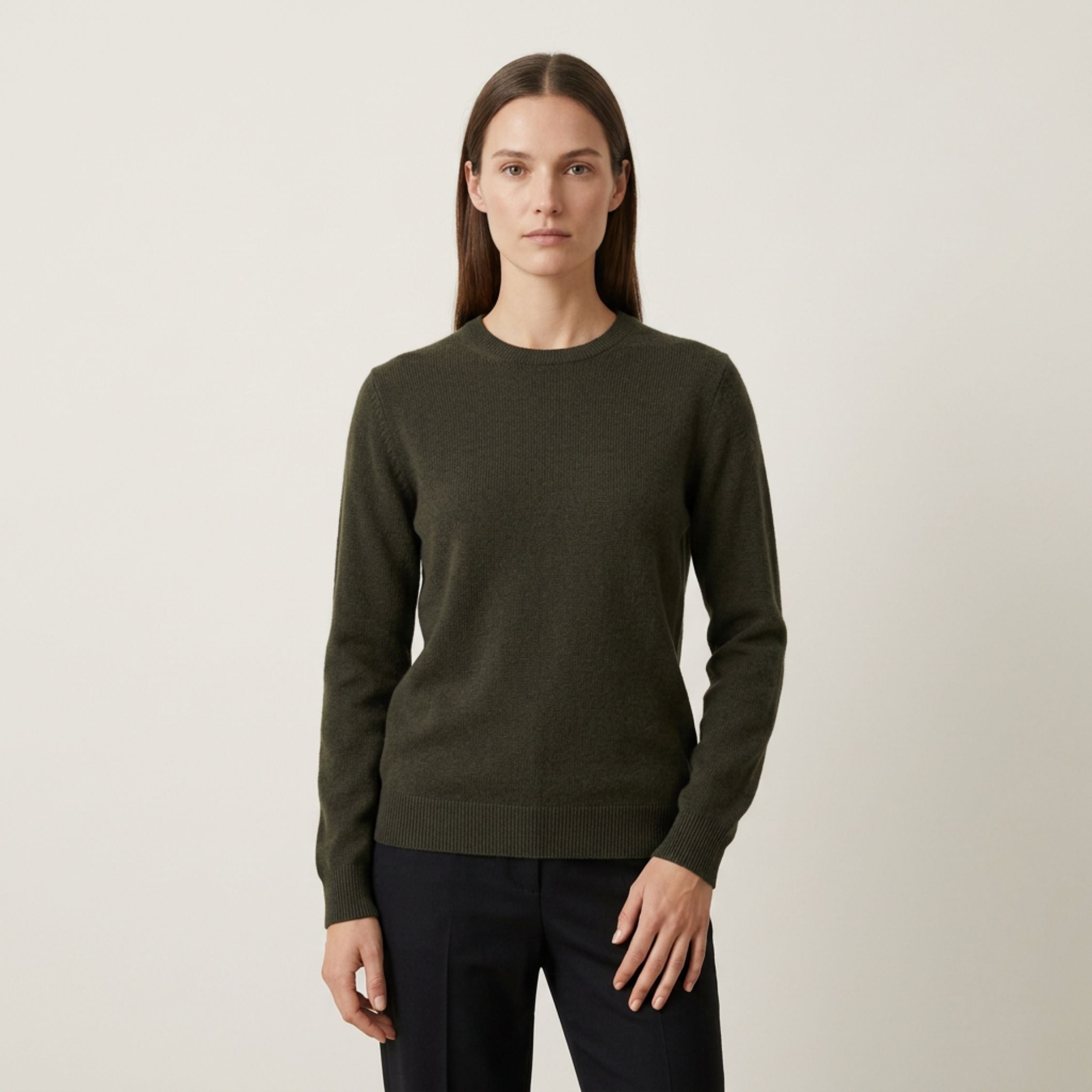 Woman wearing a green 100% Cashmere sweater against a plain background.