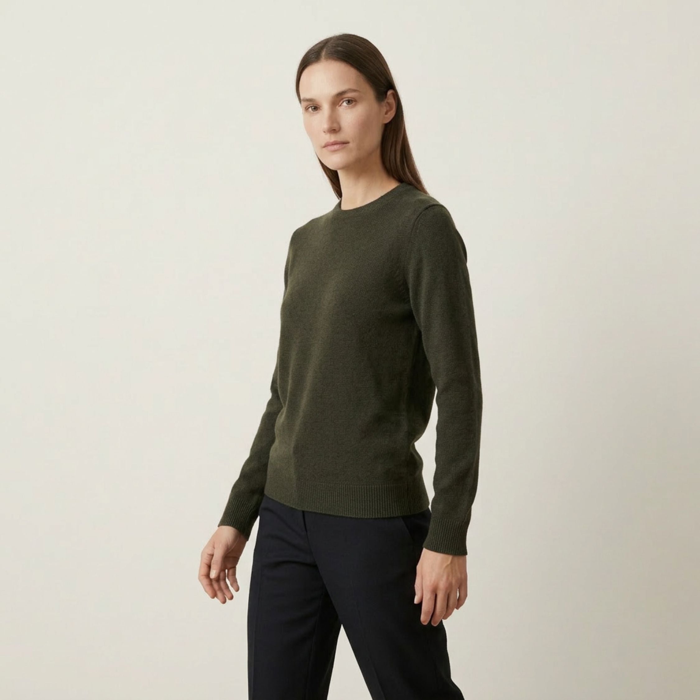 Woman wearing a green 100% Cashmere sweater and black pants on a plain background.
