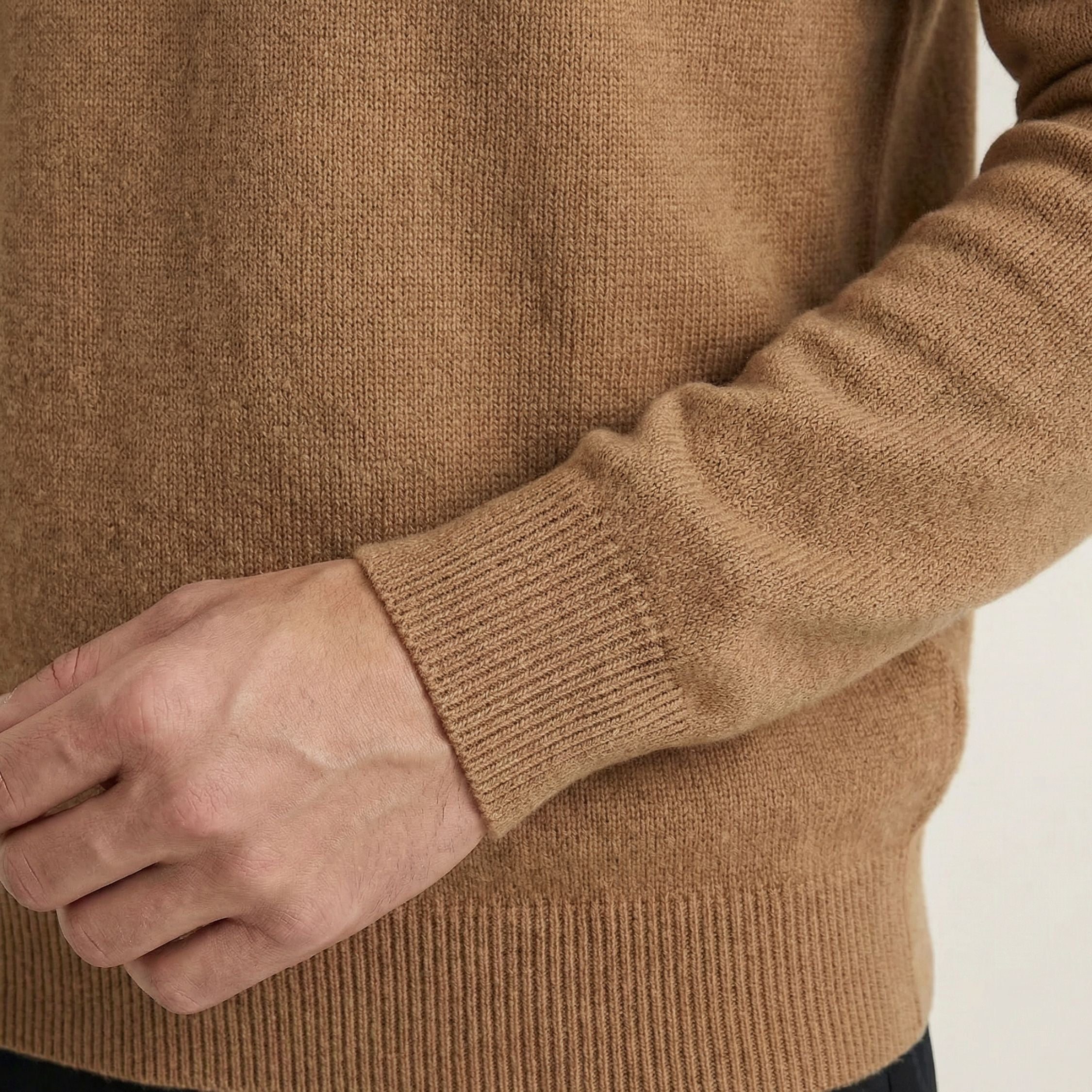 Close-up of a person wearing a brown 100% Cashmere sweater with a neutral background.
