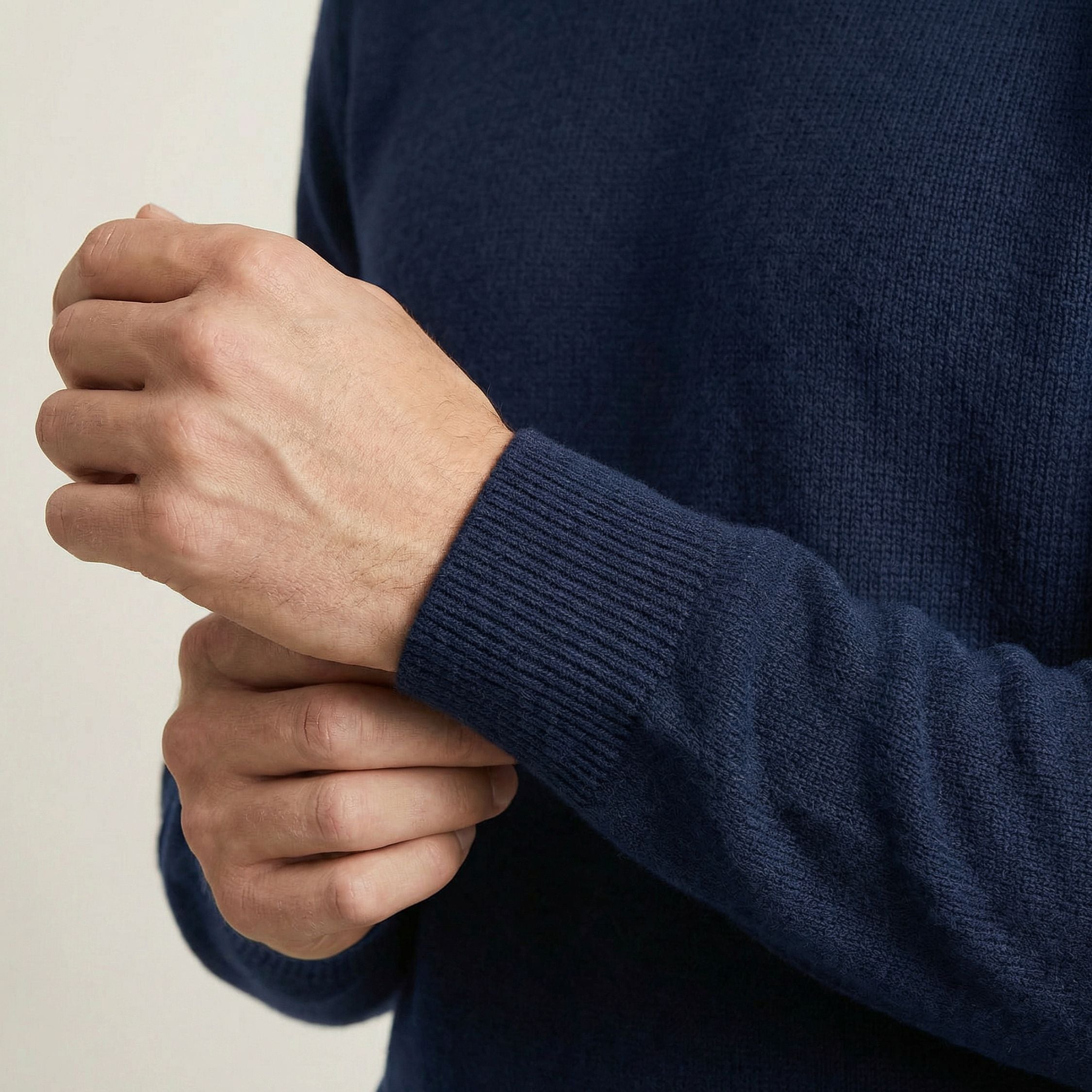 Person wearing a navy blue 100% Cashmere sweater with a close-up of their hands.