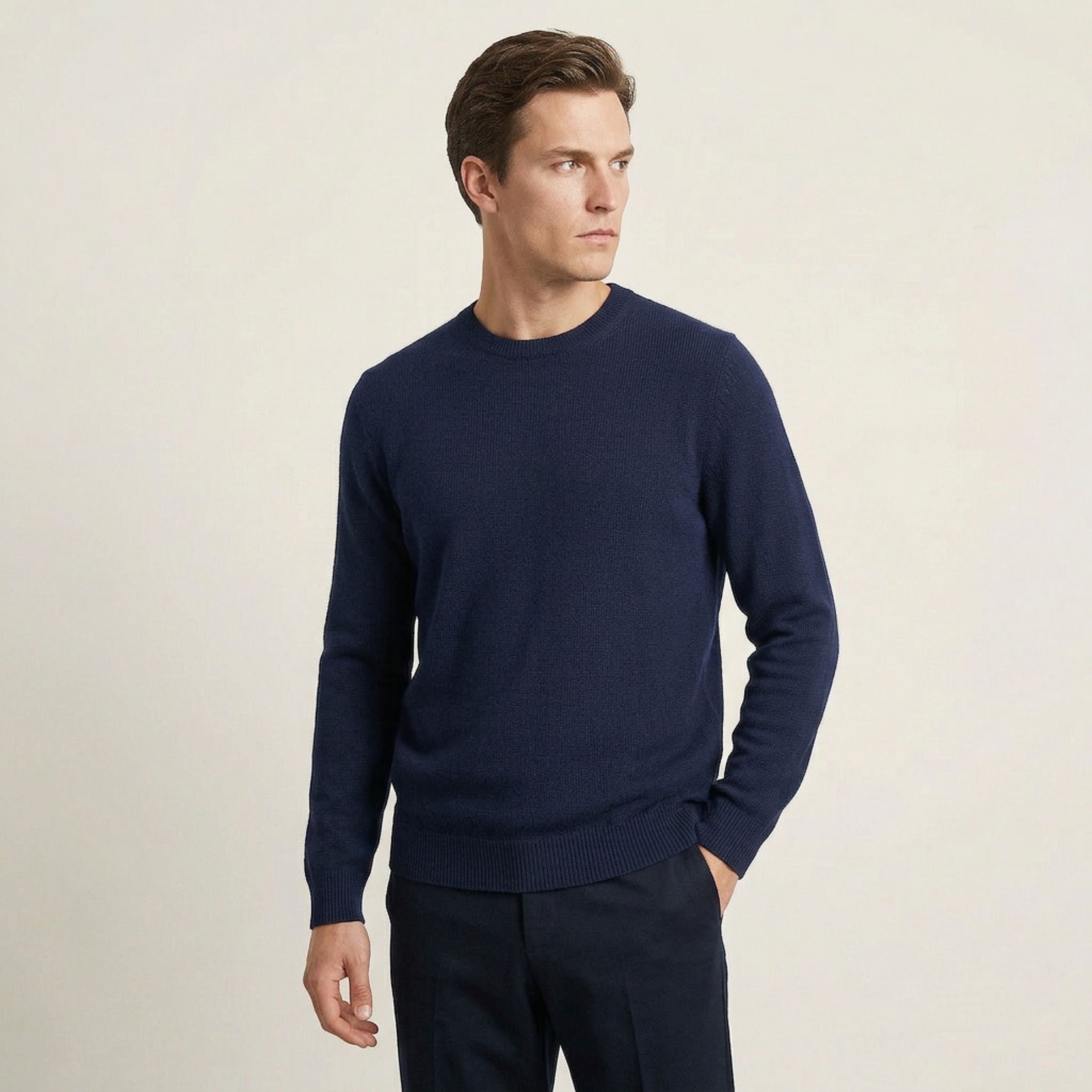 Man wearing a navy 100% Cashmere sweater and pants on a beige background.