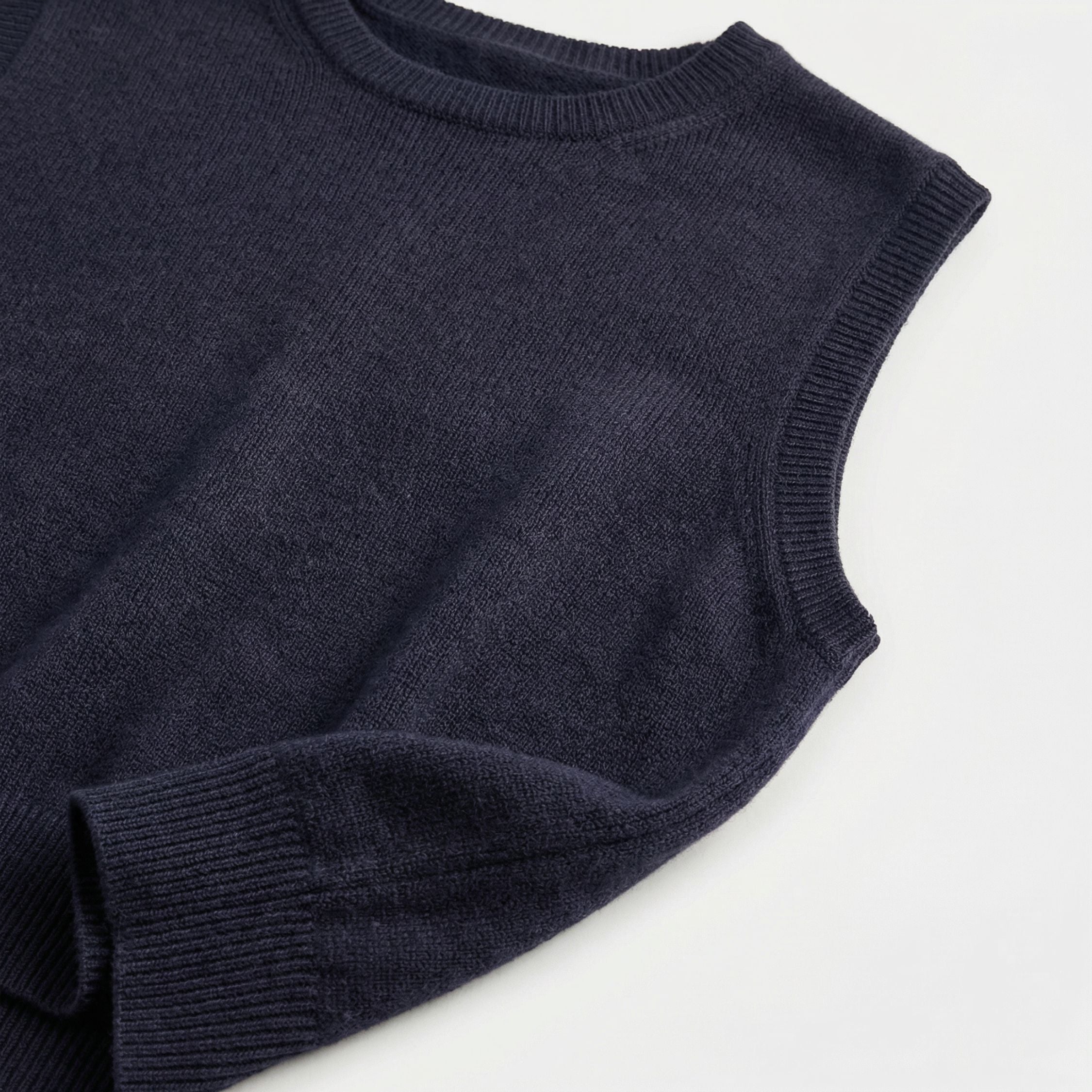 Close-up of an navy Blue 2-ply cashmere Crop sleeveless, showcasing the fine 13-gauge single jersey stitch and a ribbed crewneck along the neckline, ribbed cuffs and hem.