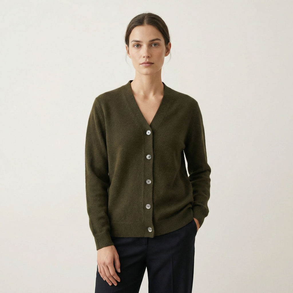 Person wearing a green 100% cashmere cardigan with a plain background