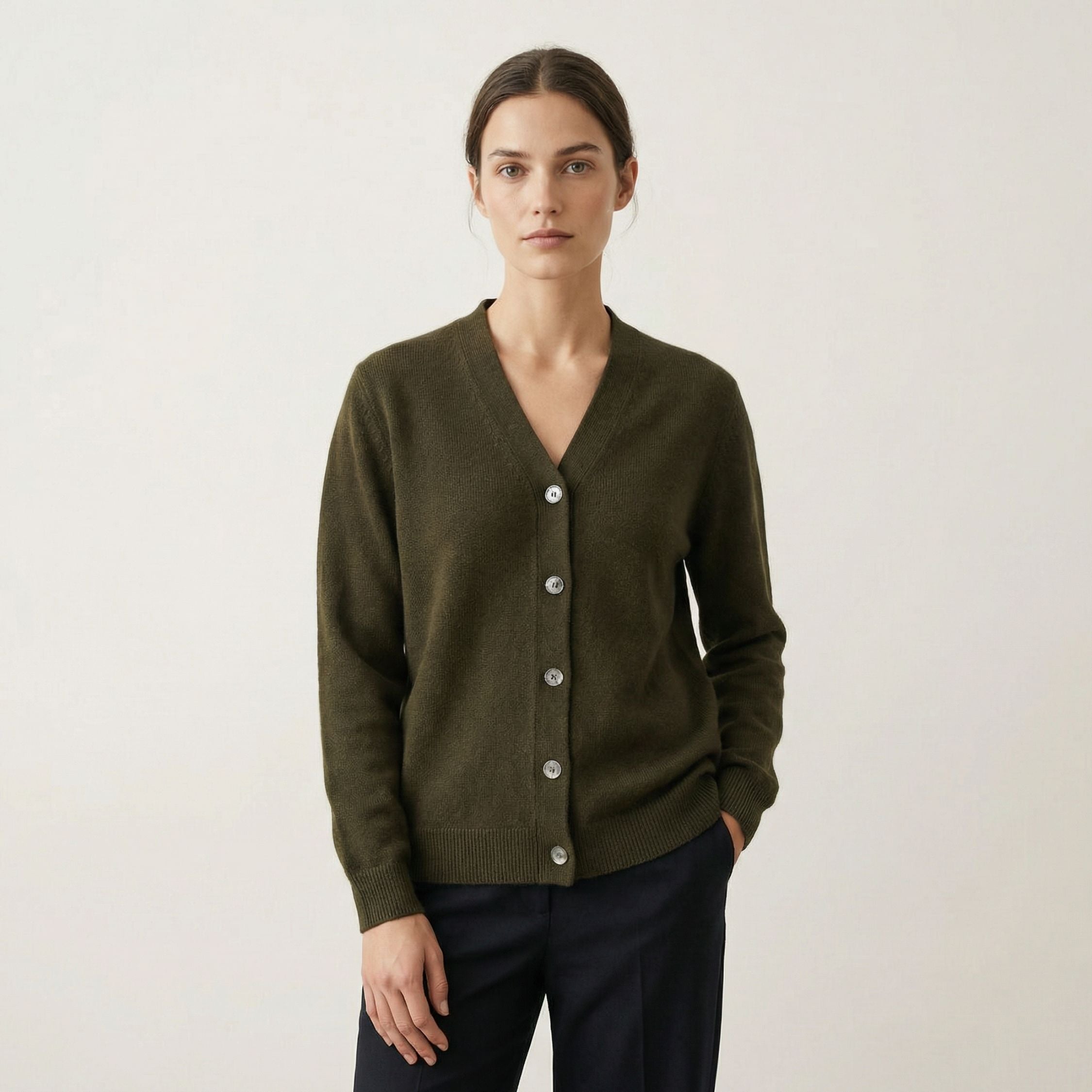 Person wearing a green 100% cashmere cardigan with a plain background