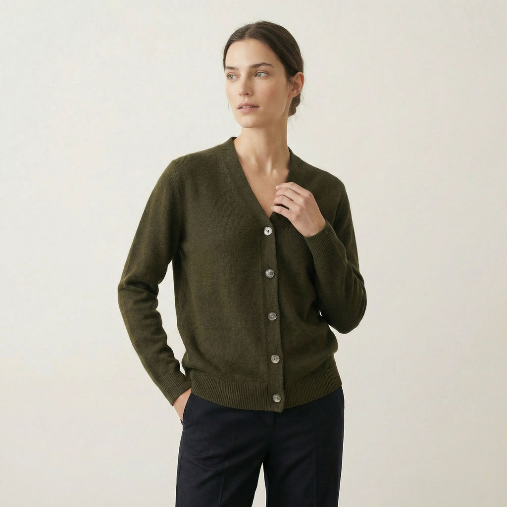 Woman wearing a green 100% cashmere cardigan against a plain background
