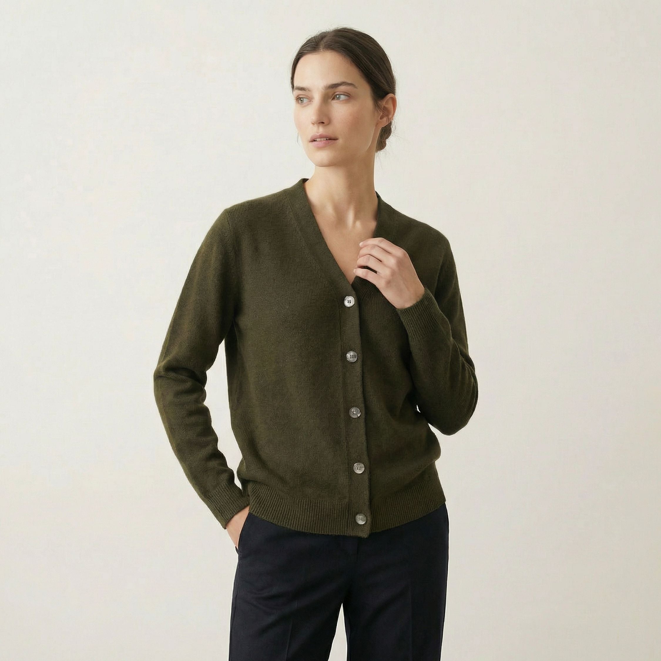Woman wearing a green 100% cashmere cardigan against a plain background