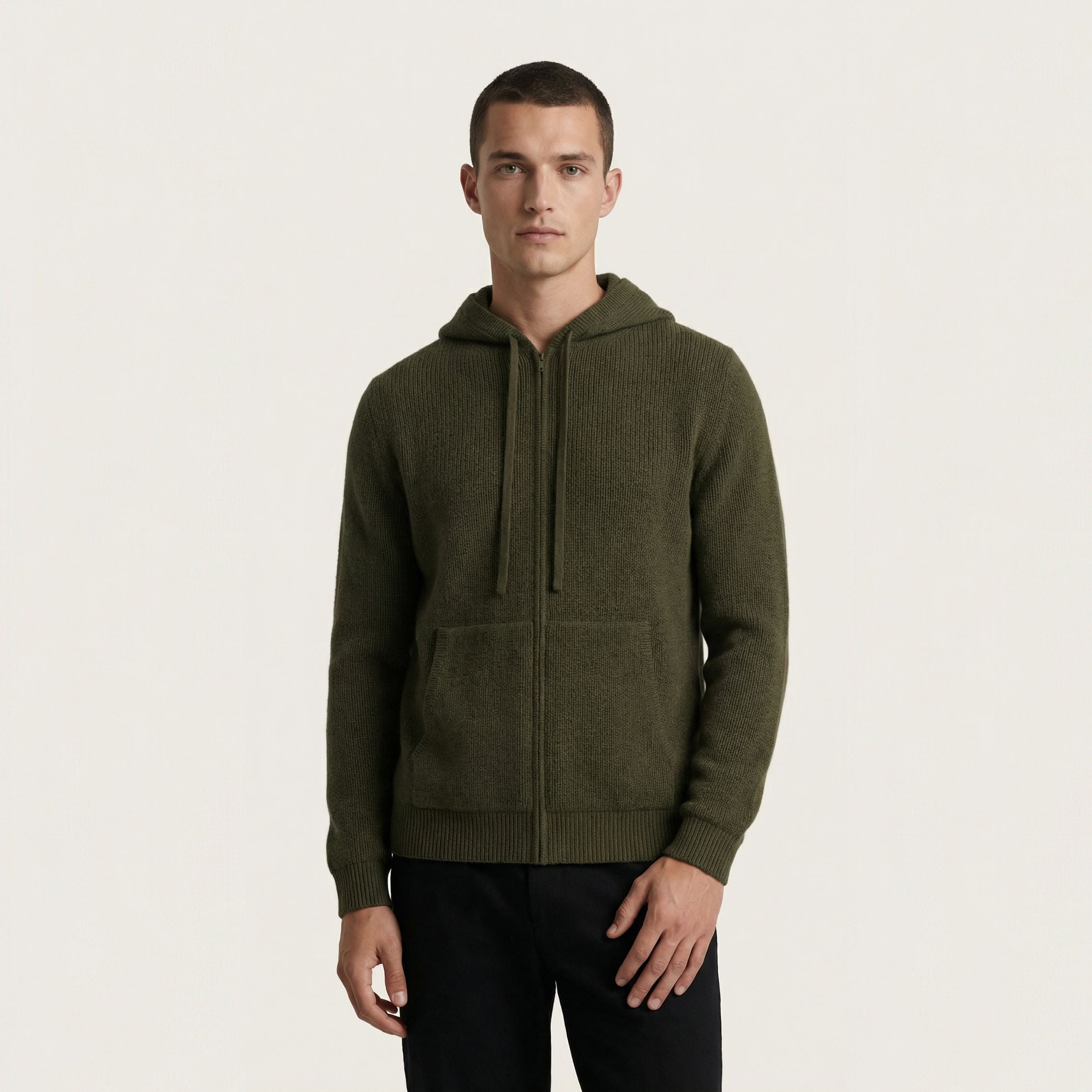 Man wearing a green 100% cashmere hoodie on a light beige background.