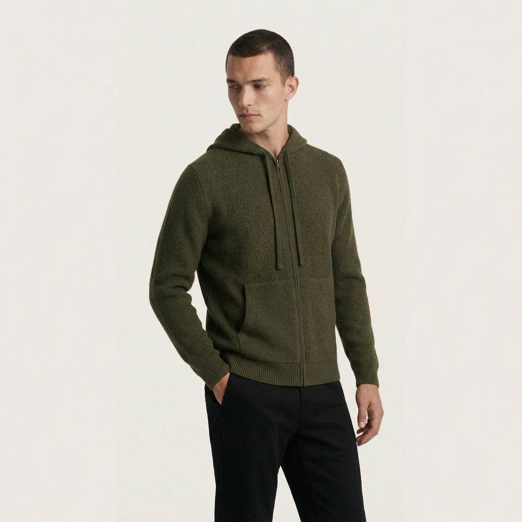 Man wearing a green 100% cashmere hoodie on a light beige background.