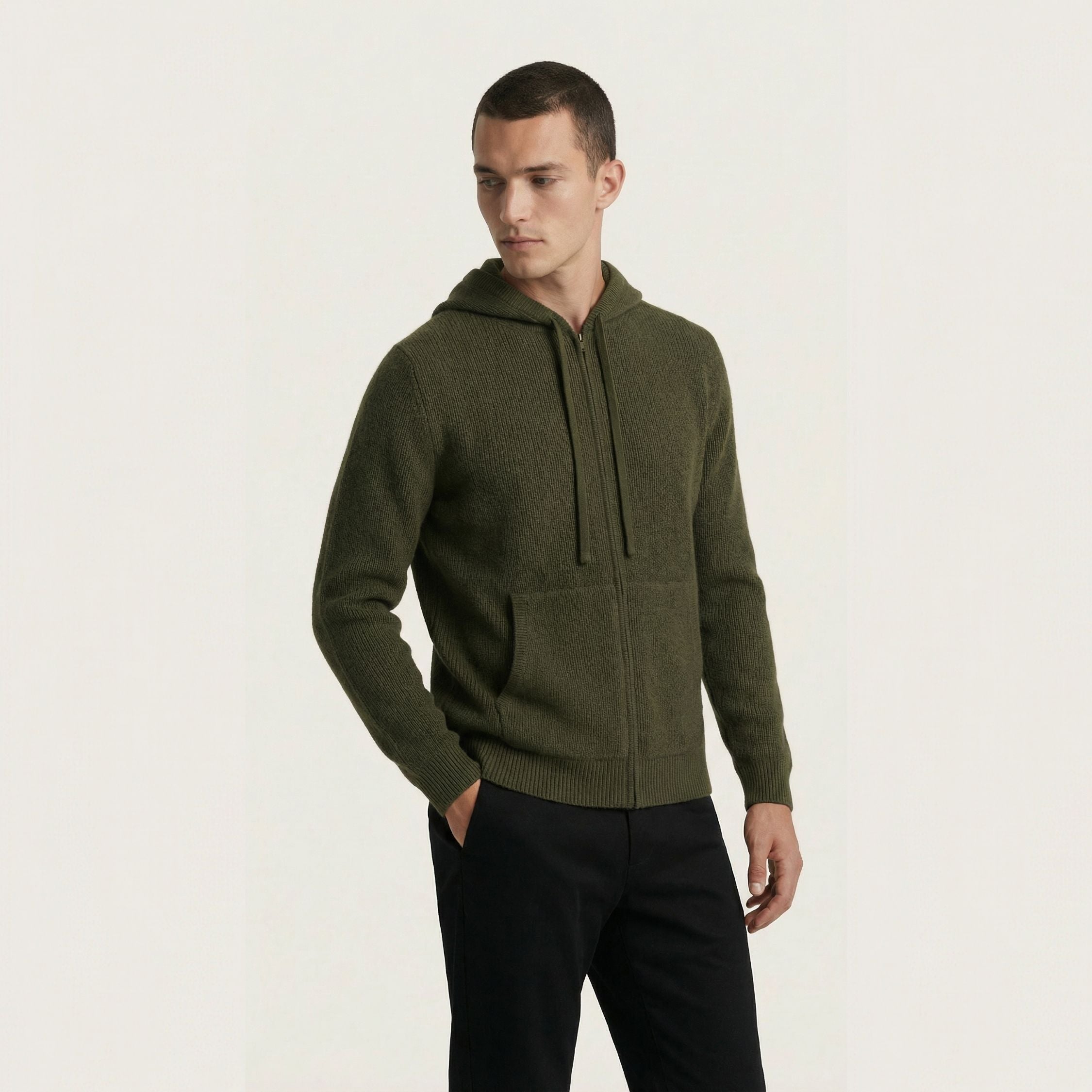Man wearing a green 100% cashmere hoodie on a light beige background.