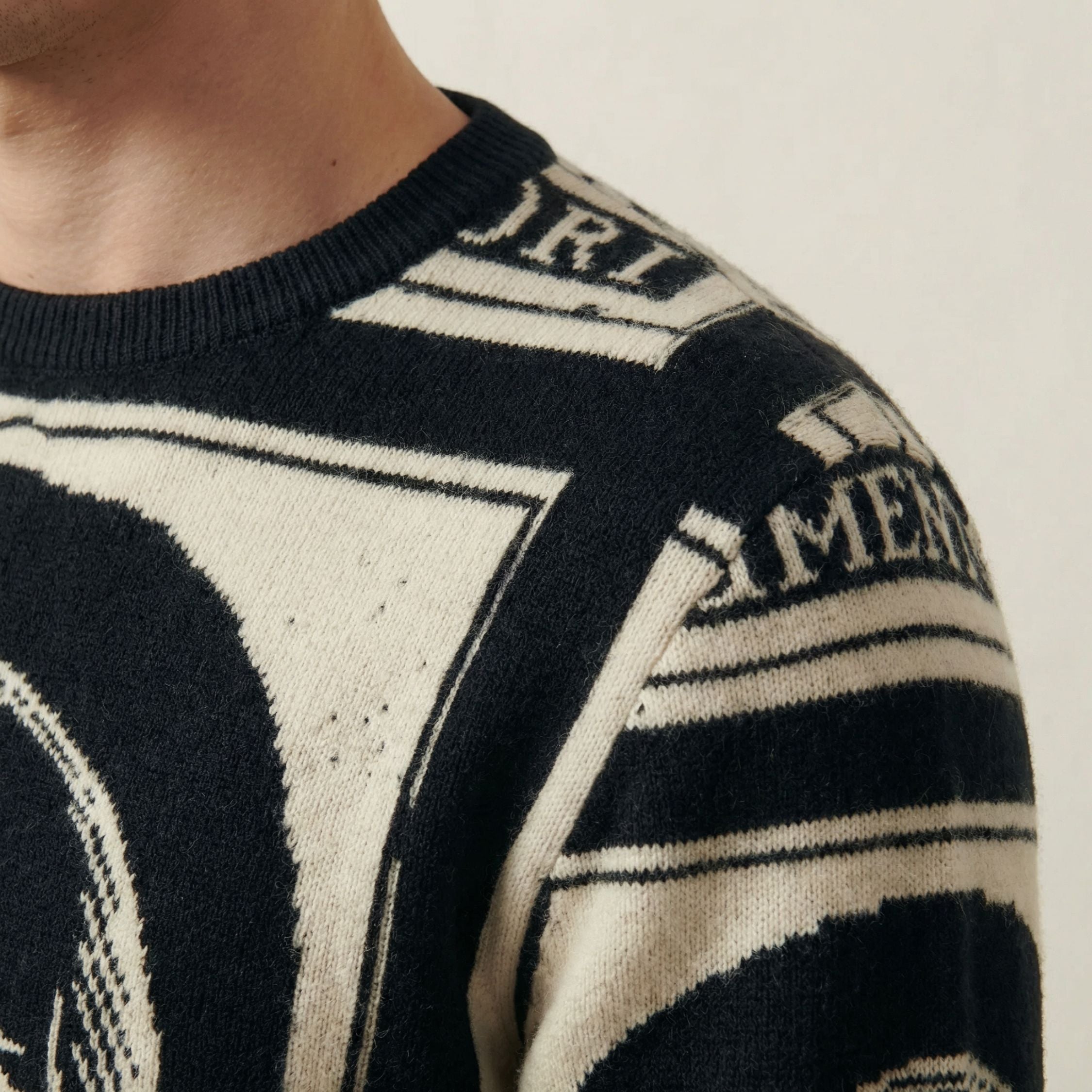 Close-up of a black and white patterned 100% cashmere sweater with text and geometric shapes.