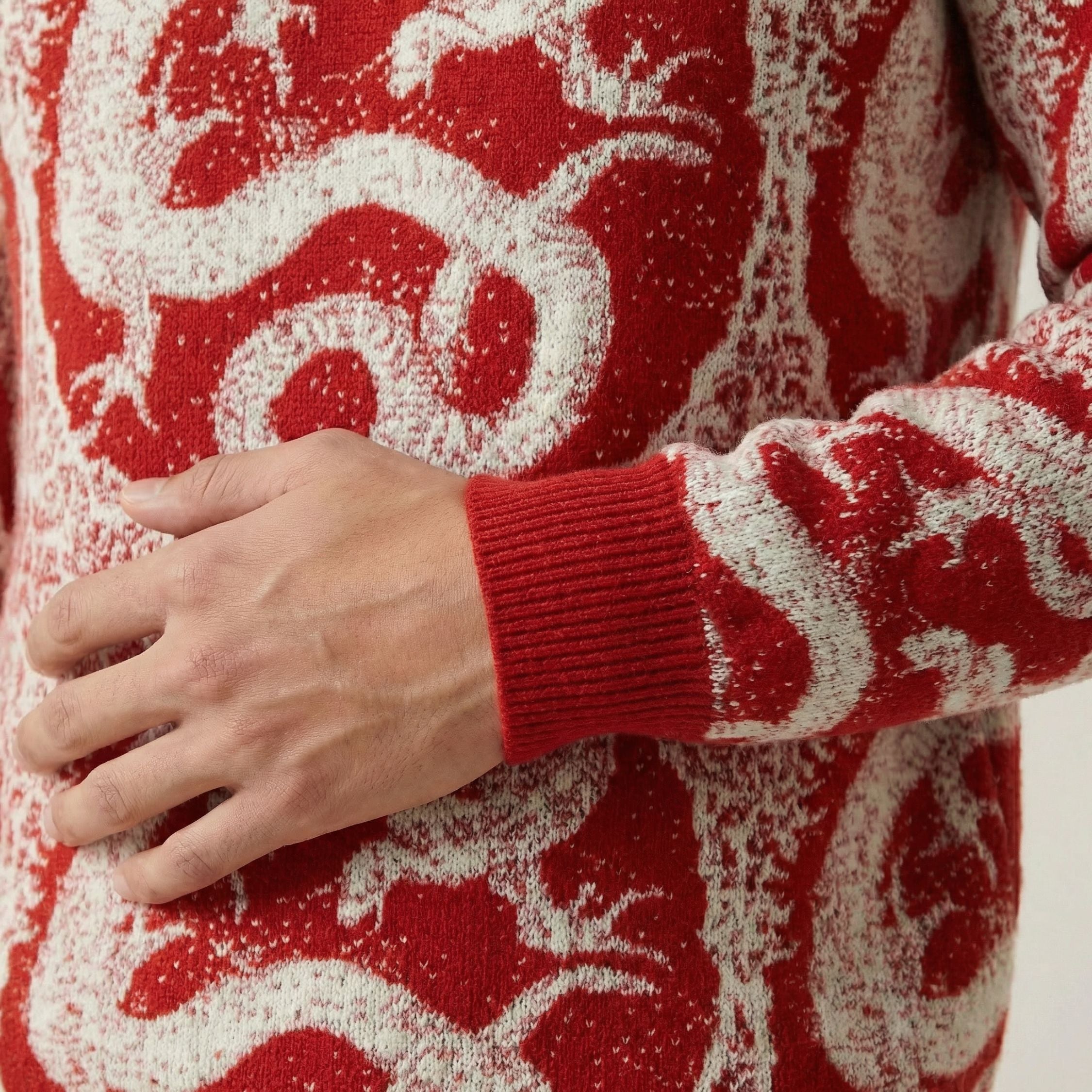 Close up of a 100% cashmere red sweater with white dragon pattern worn by a person