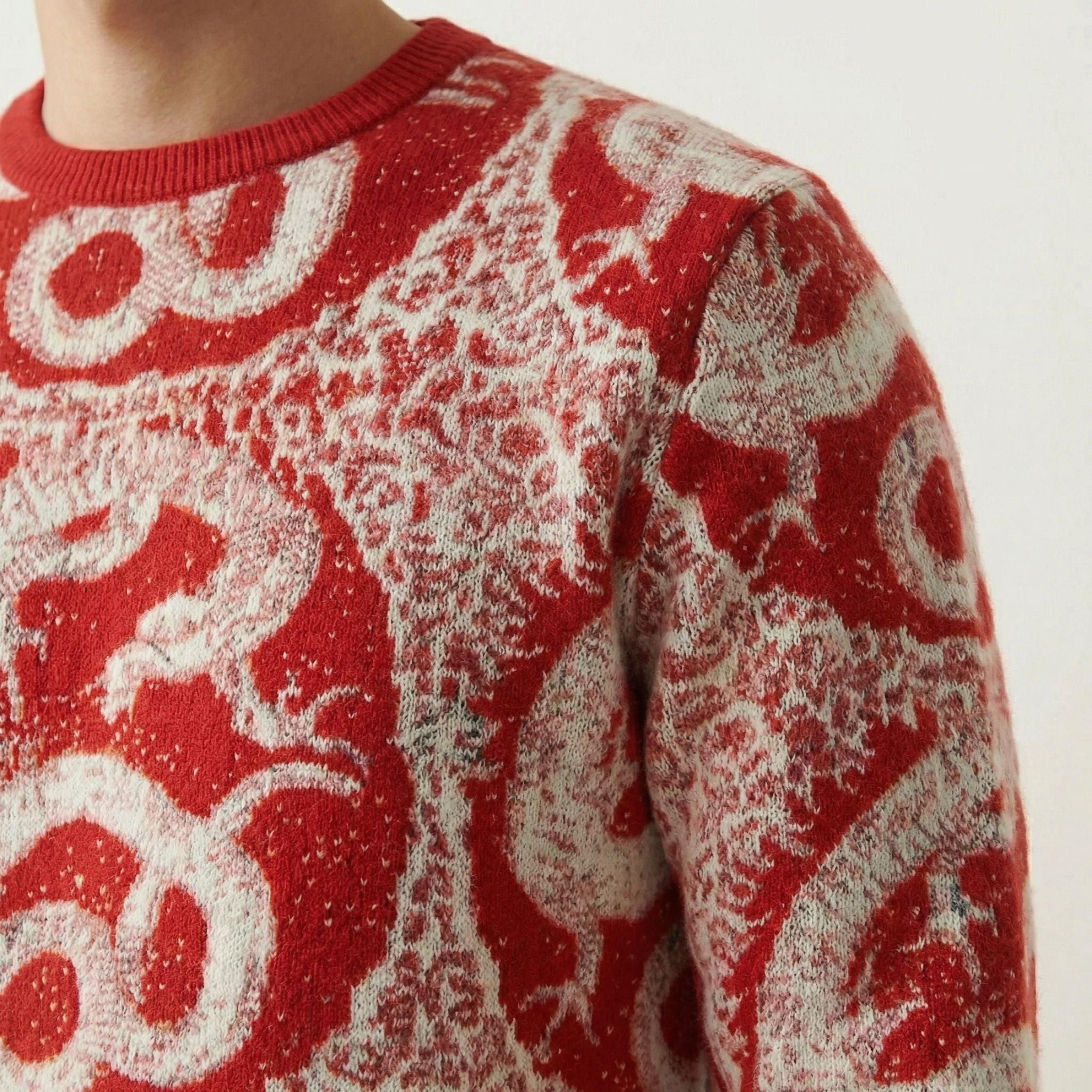 Close up of a 100% cashmere Red and white patterned sweater with dragon design on a neutral background