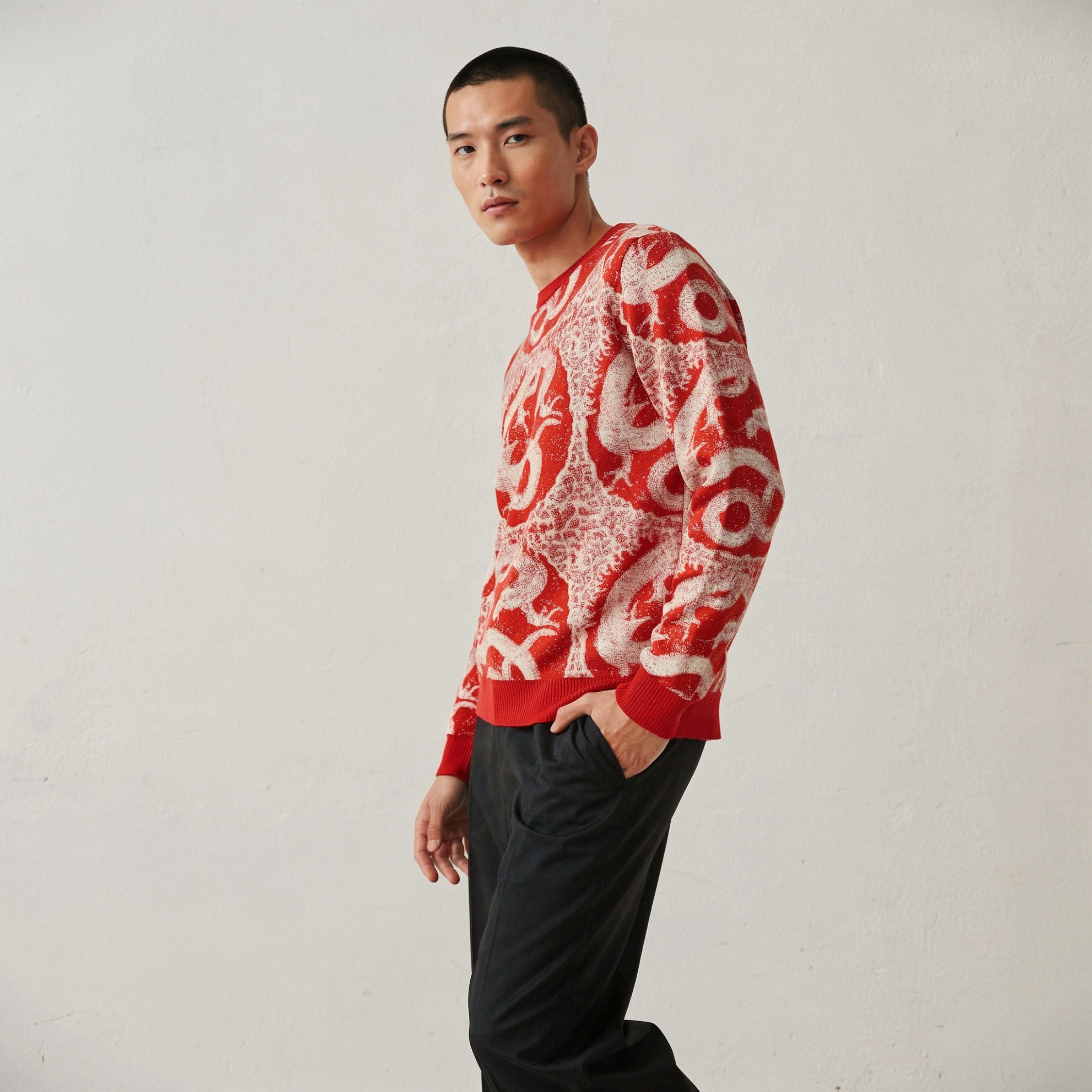Man wearing a 100% cashmere red and white patterned sweater against a plain background.