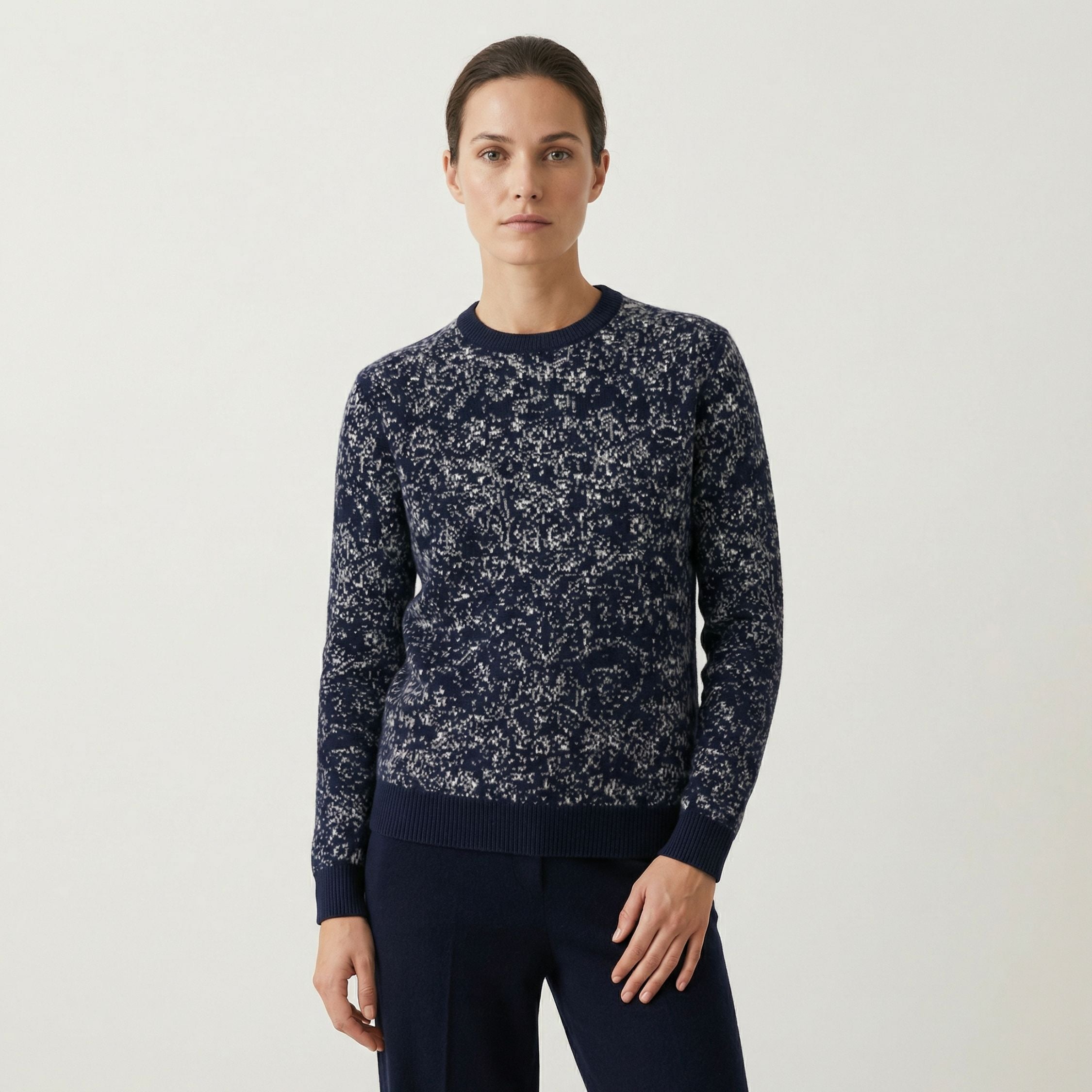 Woman wearing a 100% cashmere navy floral-patterned sweater on a light gray background