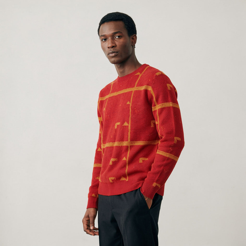 Man wearing a 100% Cashmere red sweater with geometric patterns on a plain background