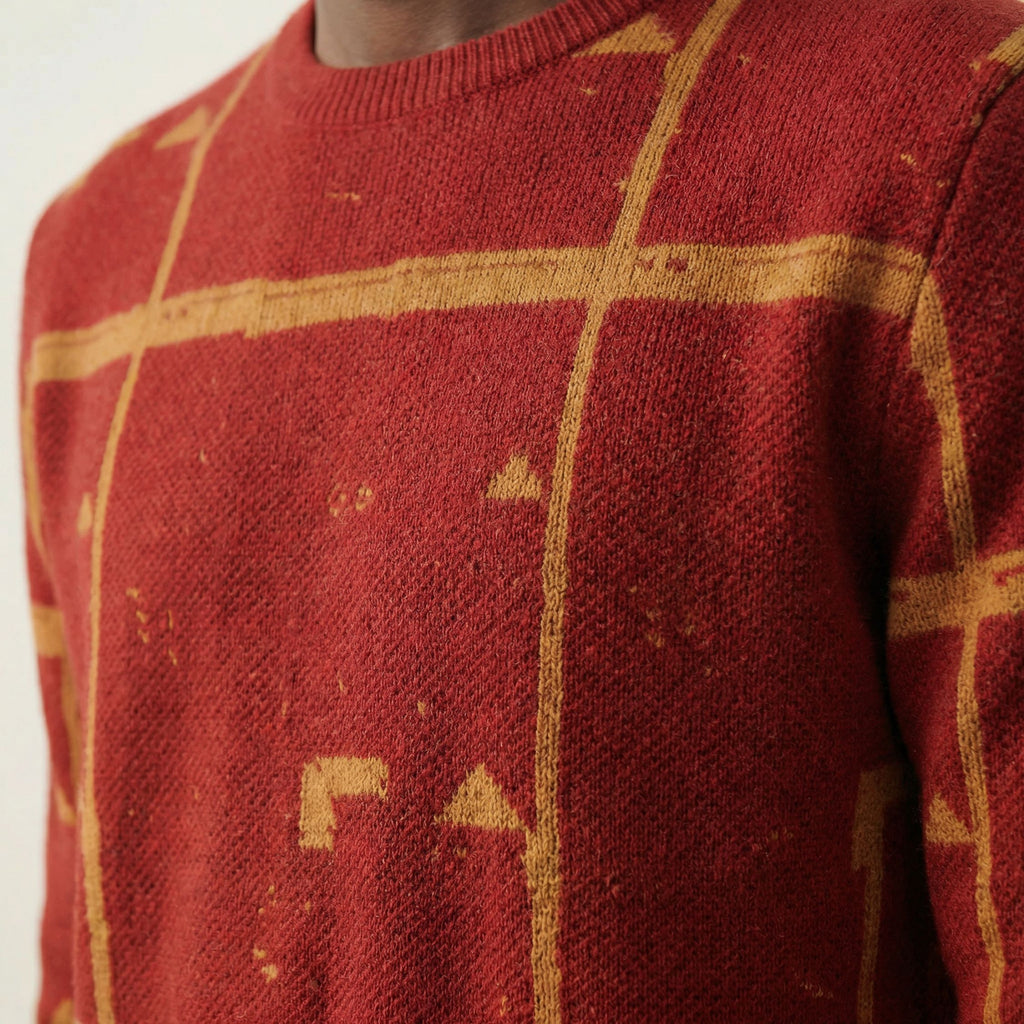 Close up macro shot of a 100% Cashmere red sweater with gold geometric patterns on a neutral background