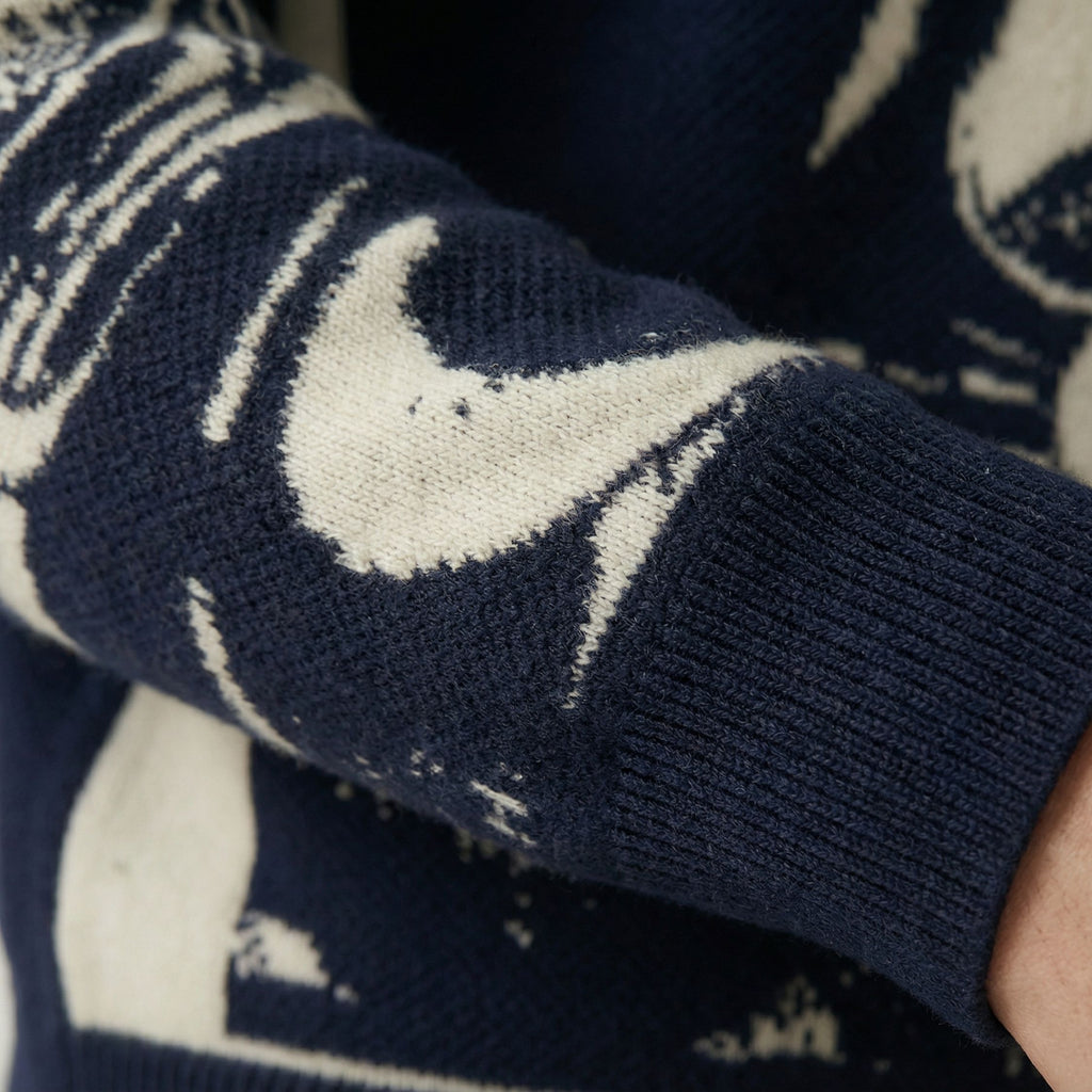Close-up of a 100% cashmere navy blue sweater with white pattern, focusing on the sleeve.