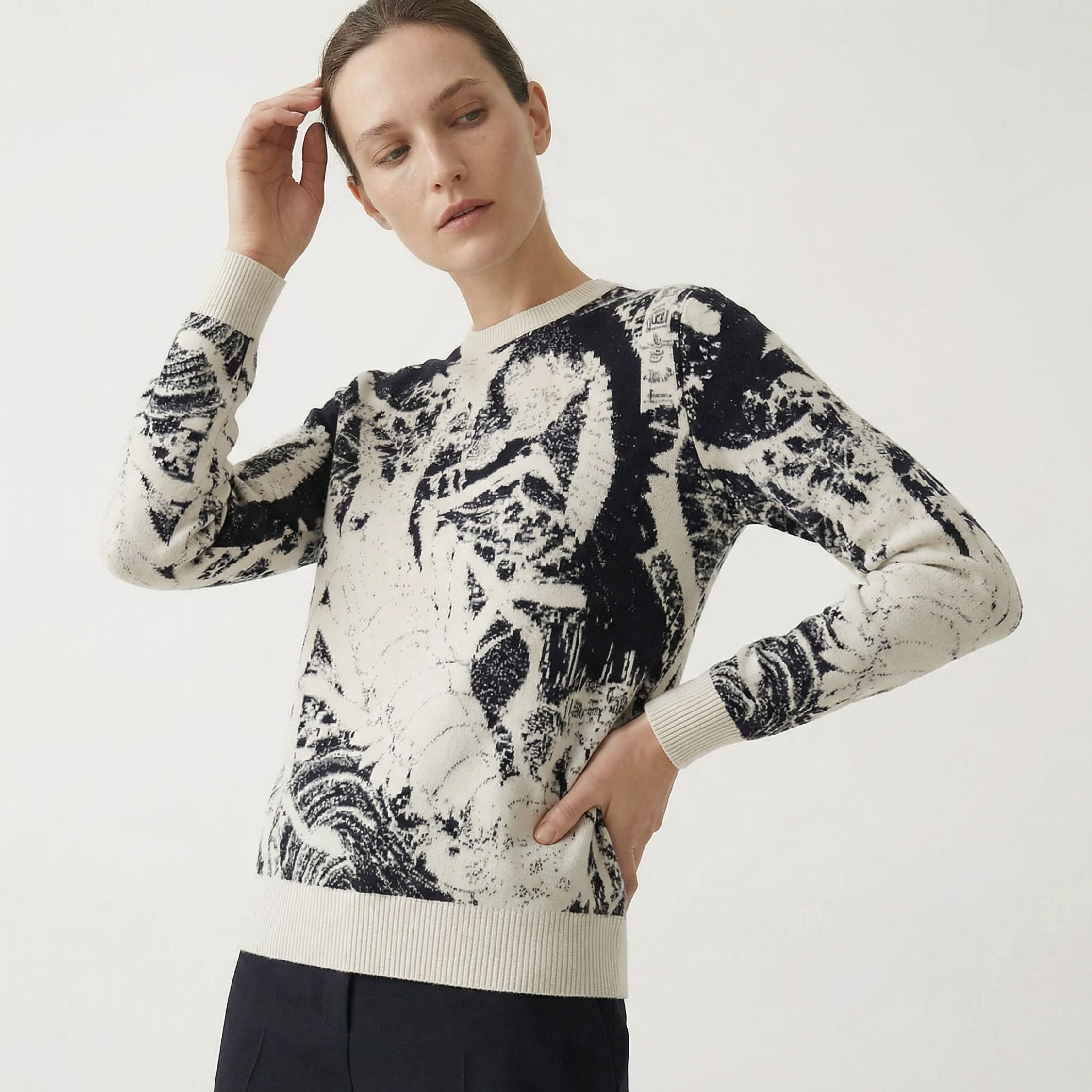 Woman wearing a black and white patterned 100% cashmere sweater on a plain background