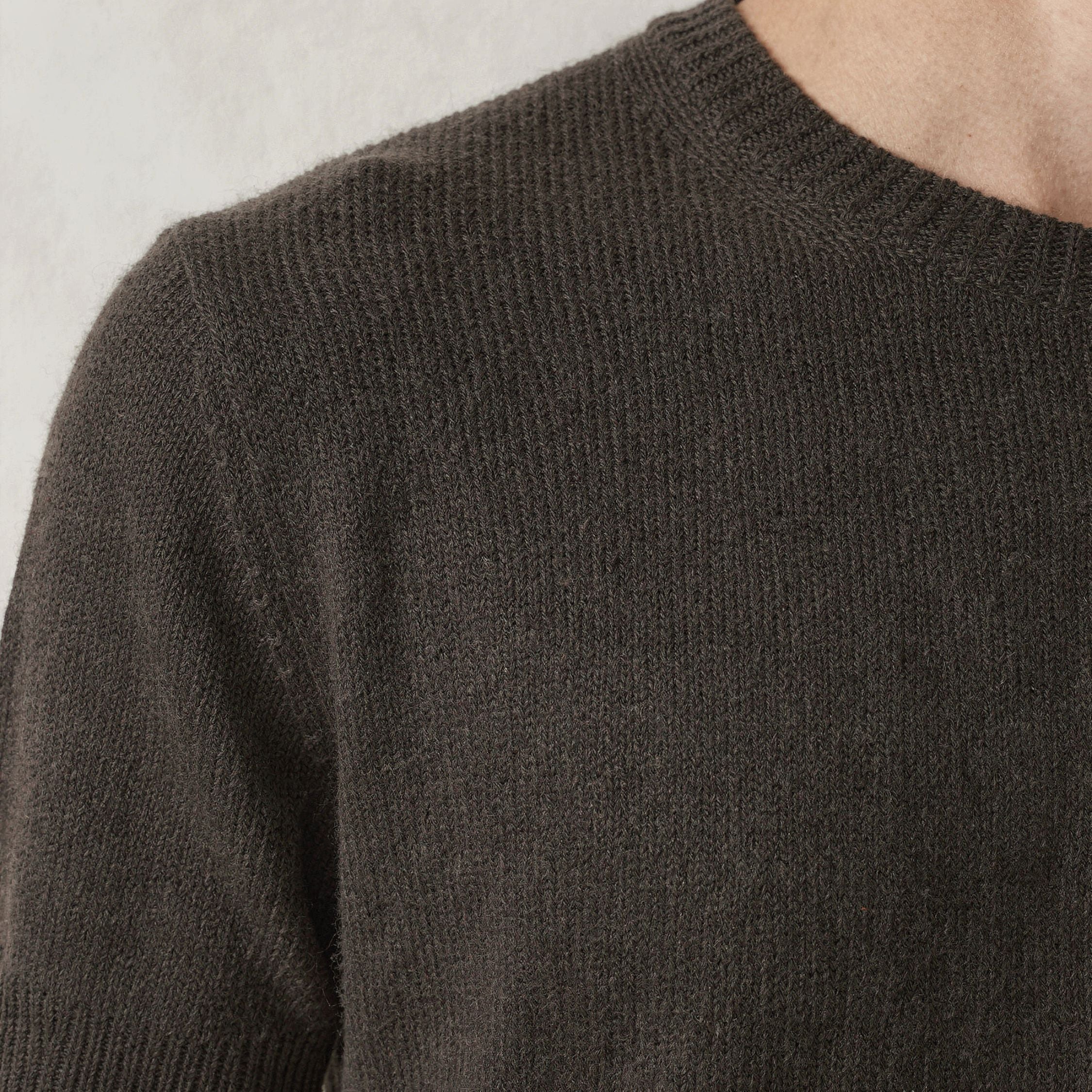 Close-up of a dark green knitted 100% cashmeret-shirt on a neutral background.