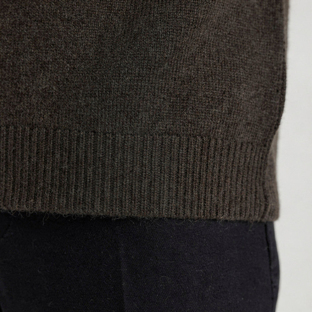 Close-up of a dark green knitted 100% cashmere t-shirt with a blurred background.
