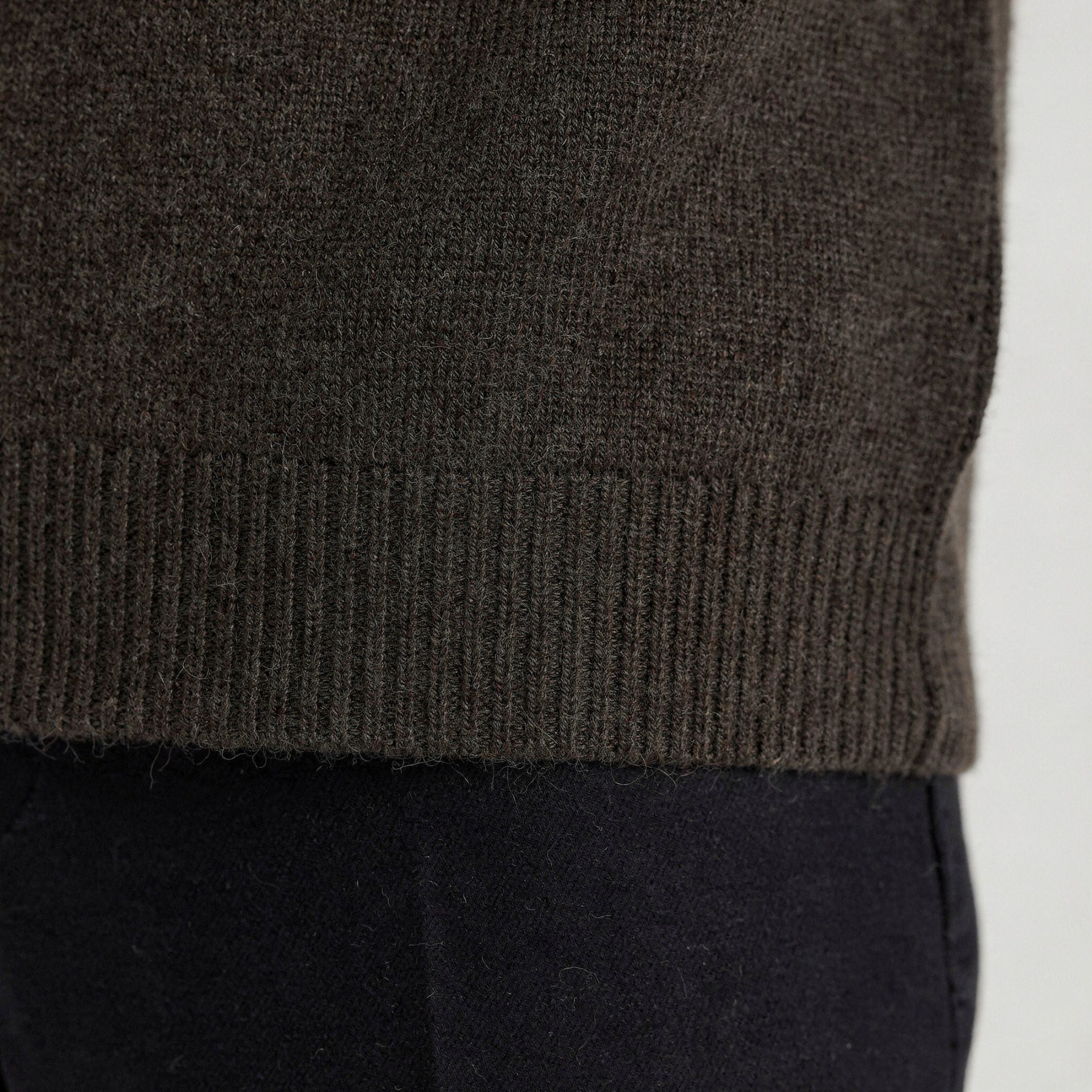 Close-up of a dark green knitted 100% cashmere t-shirt with a blurred background.