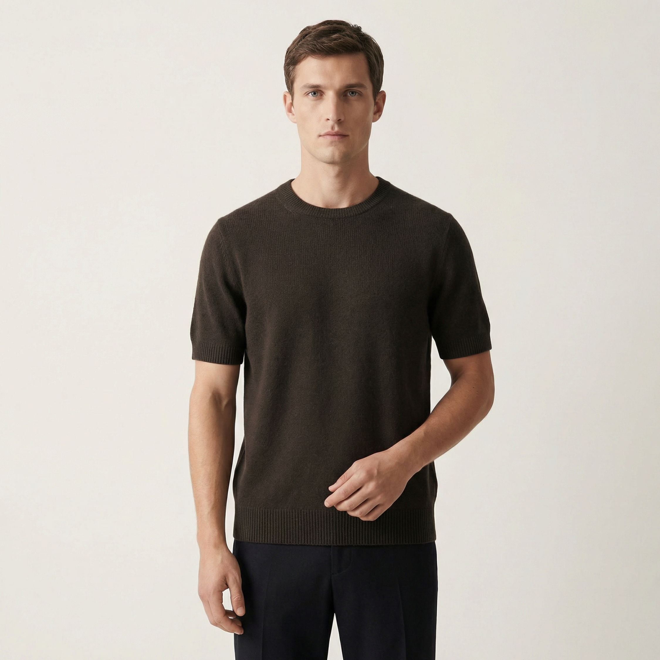 Man wearing a Dark green short-sleeve 100% cashmere sweater against a plain background.