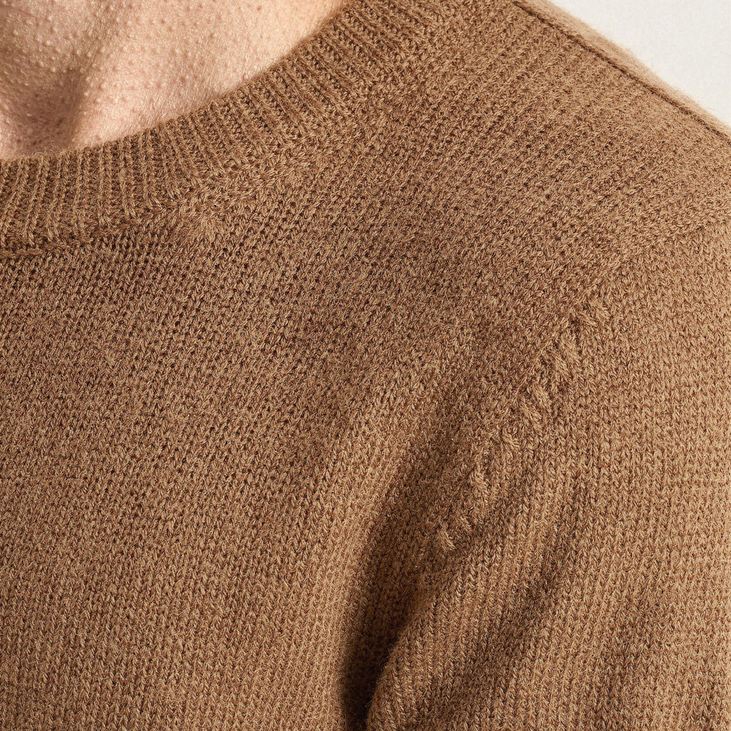 Close-up of a brown knitted 100% cashmere sweater with visible texture.