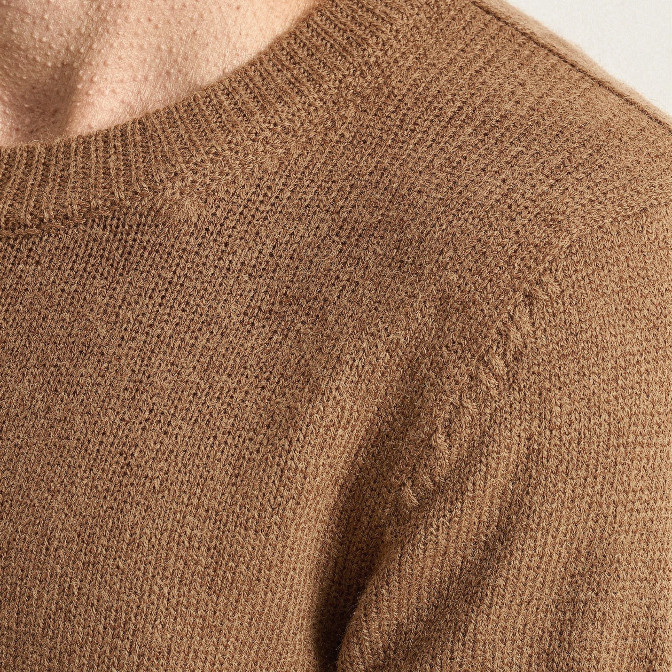 Close-up of a brown knitted 100% cashmere sweater with visible texture.