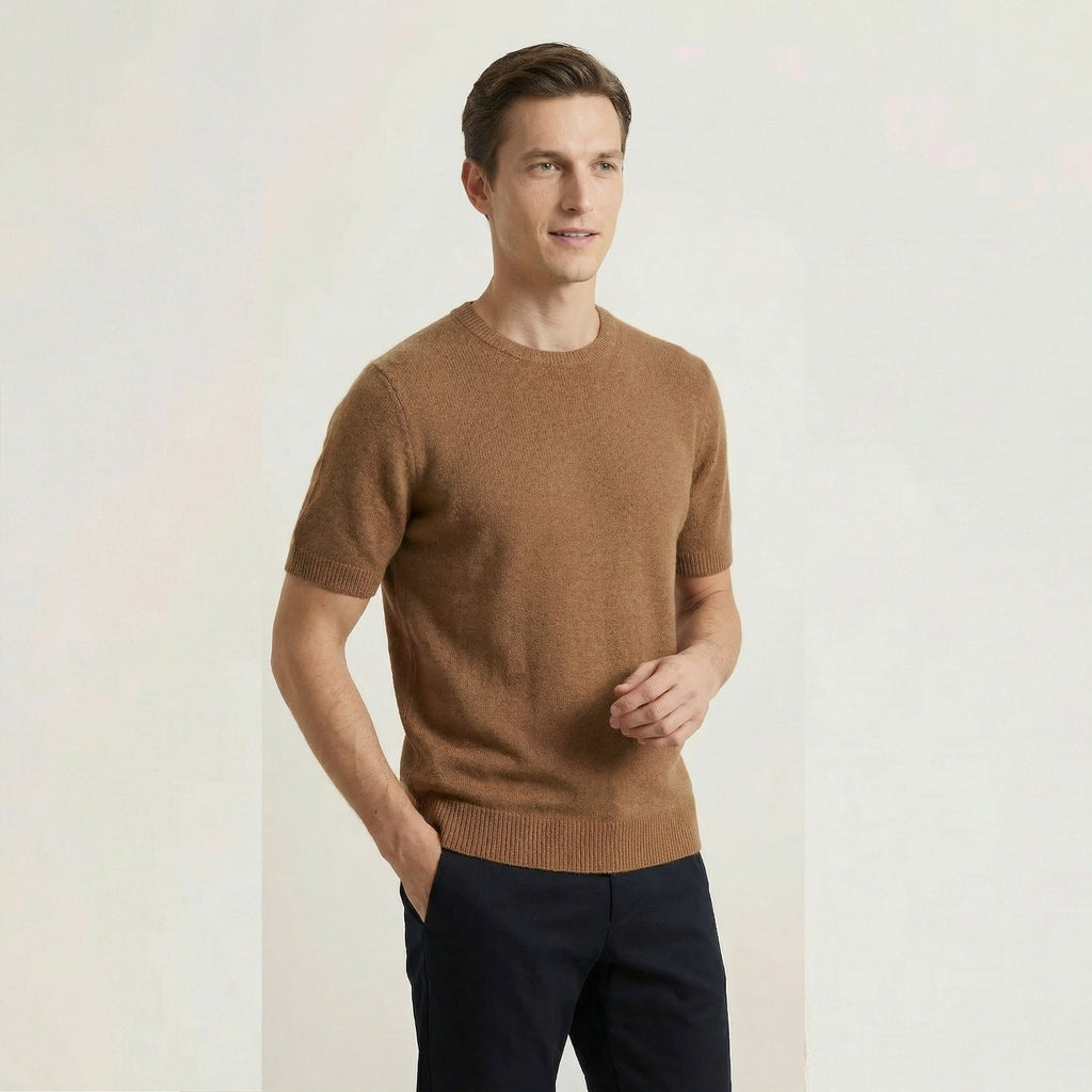 Man wearing a brown 100% cashmere sweater and dark pants on a light background.