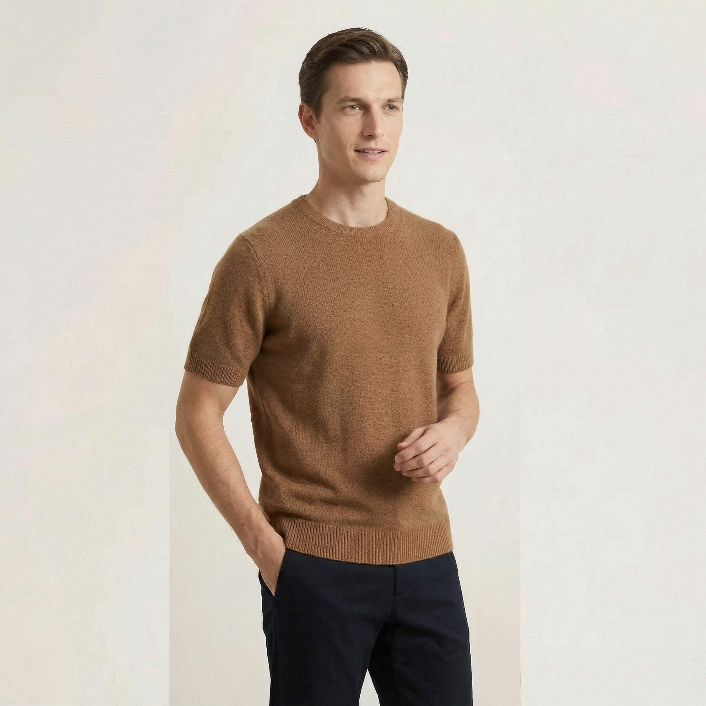Man wearing a brown 100% cashmere sweater and dark pants on a light background.